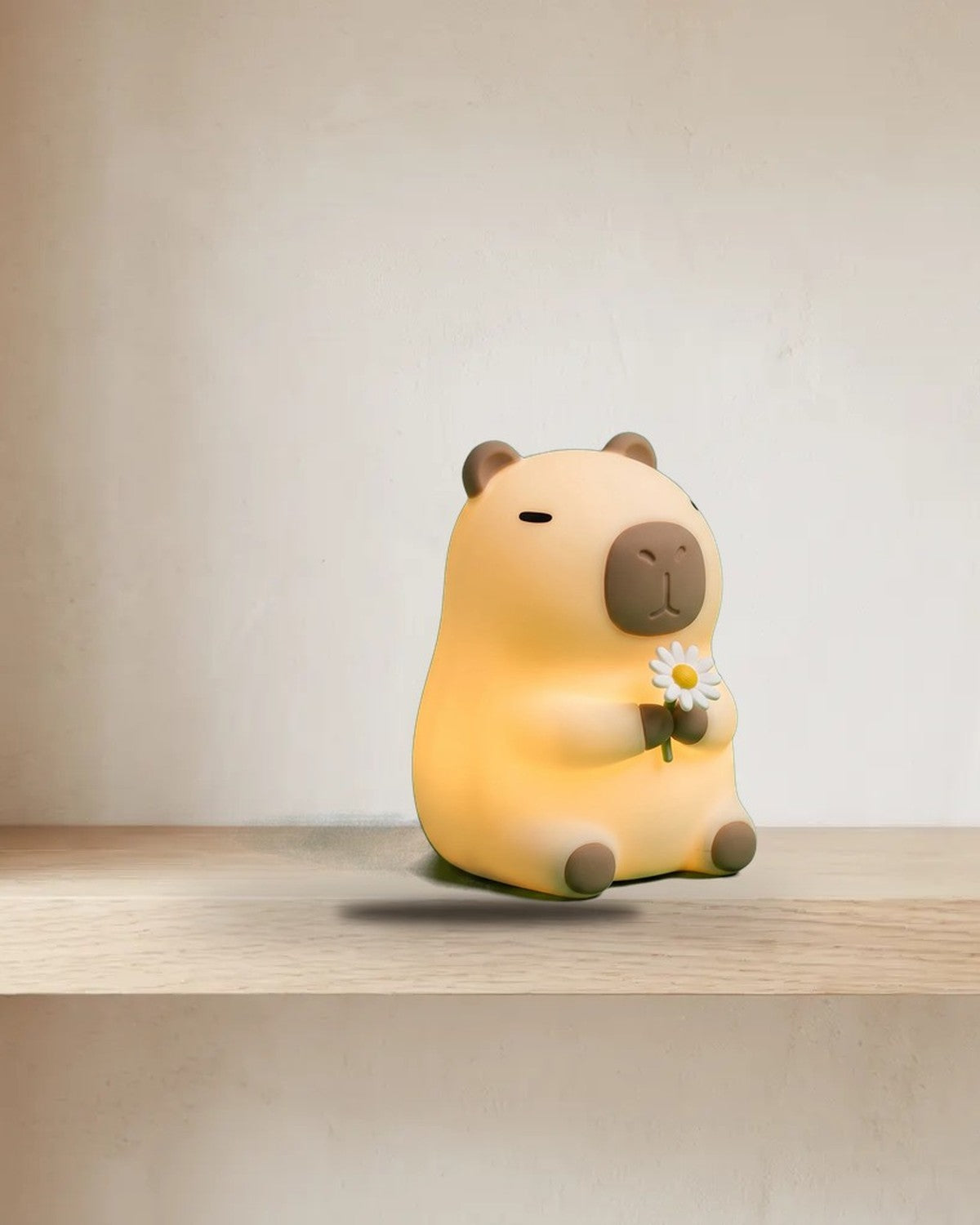 Soft silicone capybara night light holding a flower, glowing warm on a shelf