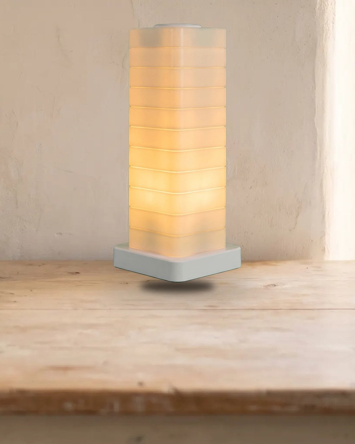 Stacked translucent block lamp glowing warm white on a wooden desk