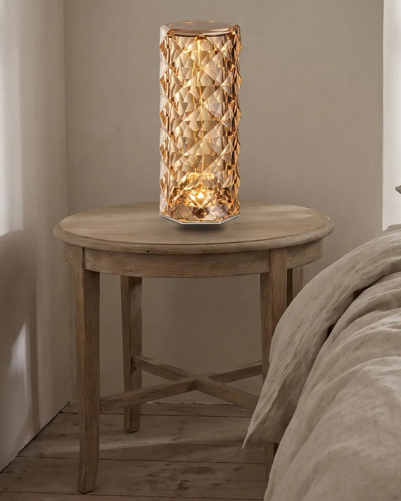 Rose-cut acrylic table lamp glowing warm on a bedside table