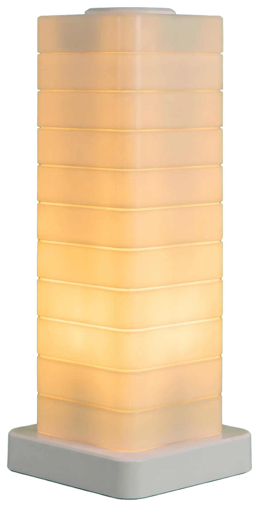 Stacked translucent block lamp glowing warm white on a dark desk