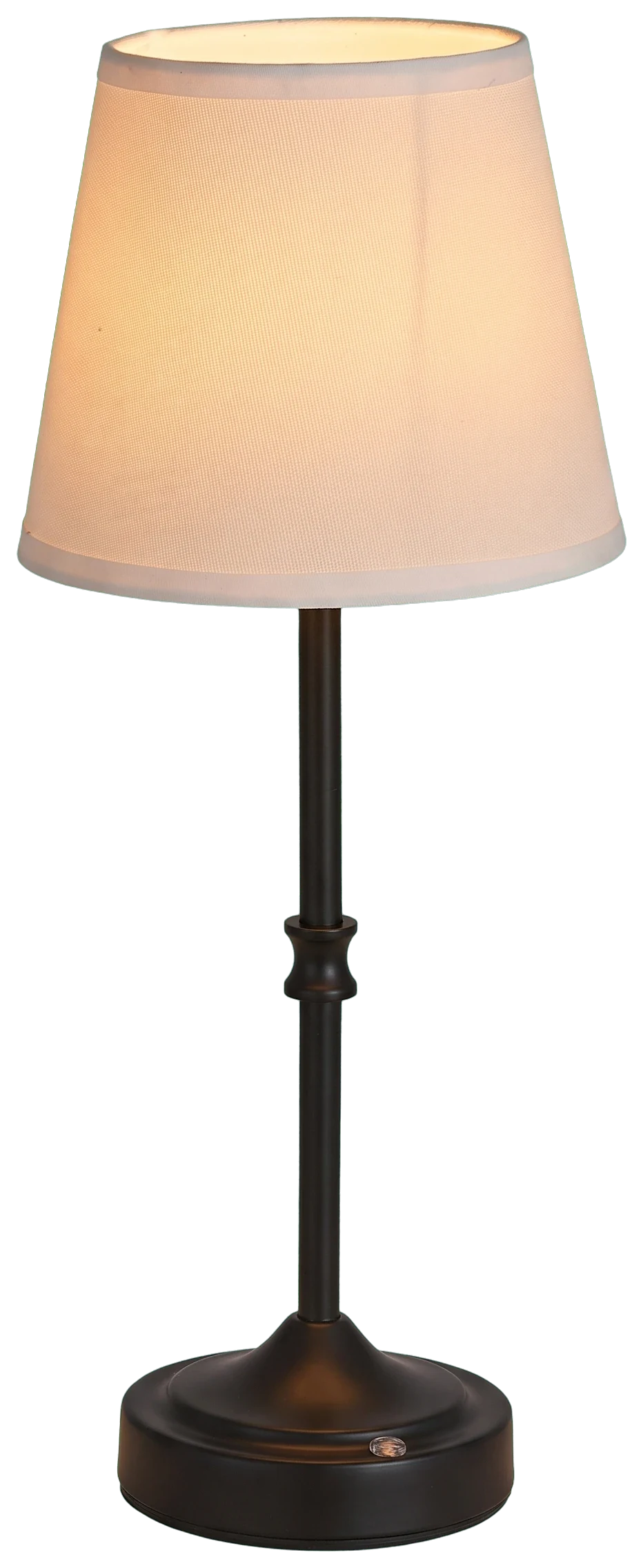 Small cordless table lamp with a fabric shade glowing warm on a dark side table